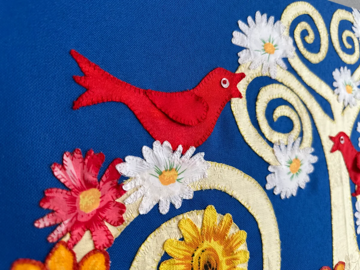 Und auch hier lassen sich wieder rote Vögel entdecken. Bild aus Stoff.